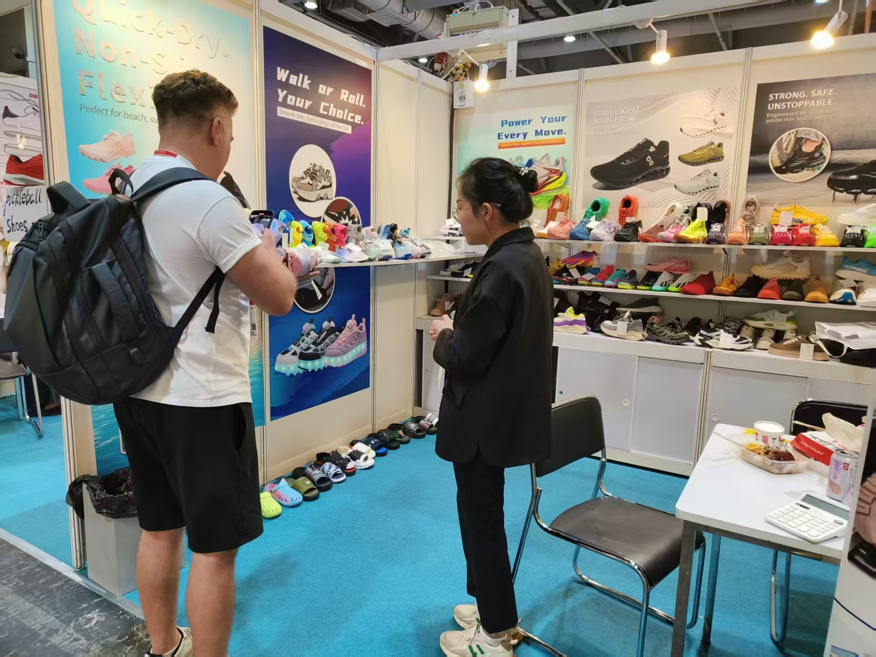 Trade-show visitor reviewing XiangChi footwear samples at the exhibition booth