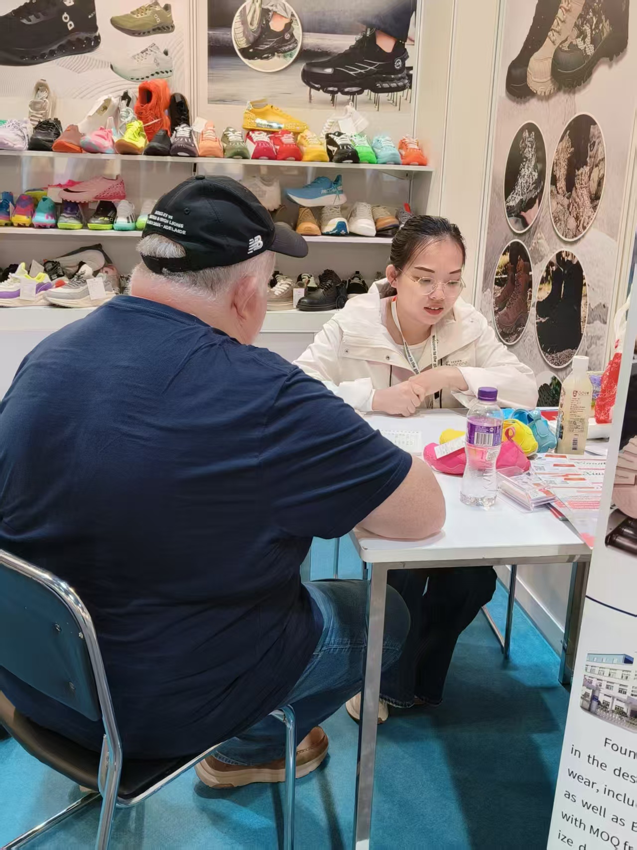 XiangChi team member discussing footwear samples with a trade-show visitor
